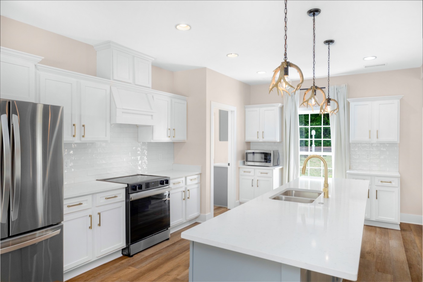 Kitchen with white cabinets, a large island and gold fixtures